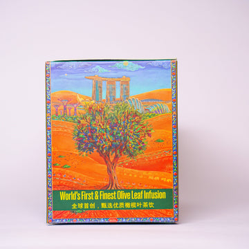 A colorful product box featuring an illustration of an olive tree in a sunlit field with ancient stone columns in the background, photographed against a plain light gray studio backdrop.