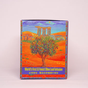 A rectangular product box standing upright against a plain light background. The box features a colorful illustration of an olive tree in a warm orange landscape with classical stone ruins under a blue sky.