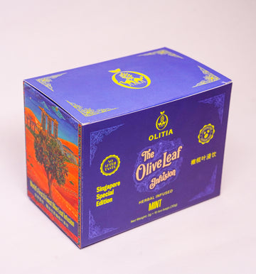 A purple cardboard box of Olitia The Olive Leaf Infusion Mini herbal infusion, featuring gold lettering and a scenic orange and blue illustration on the side, set against a plain light background.